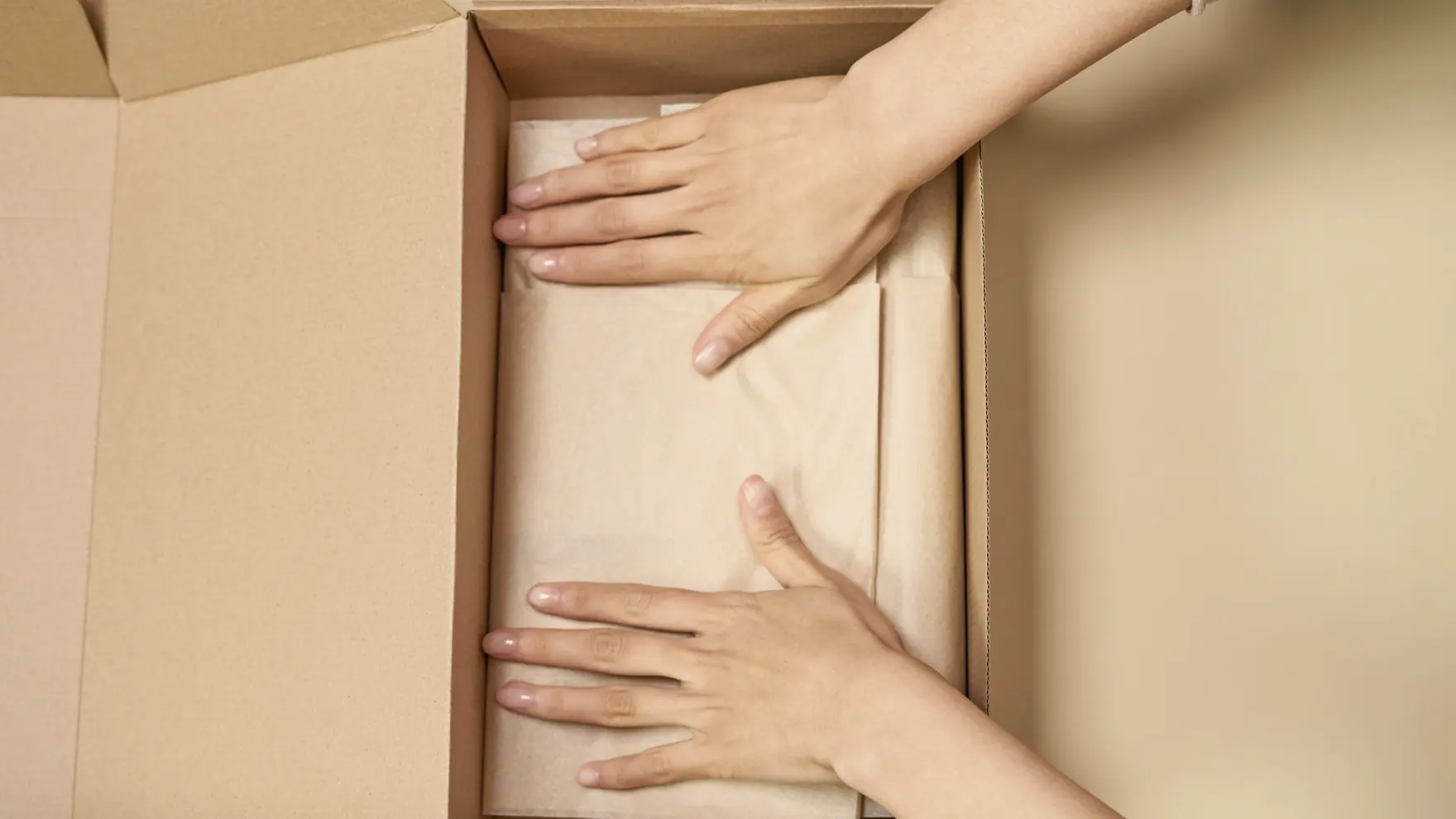 Hands smoothing tissue paper into an open order box
